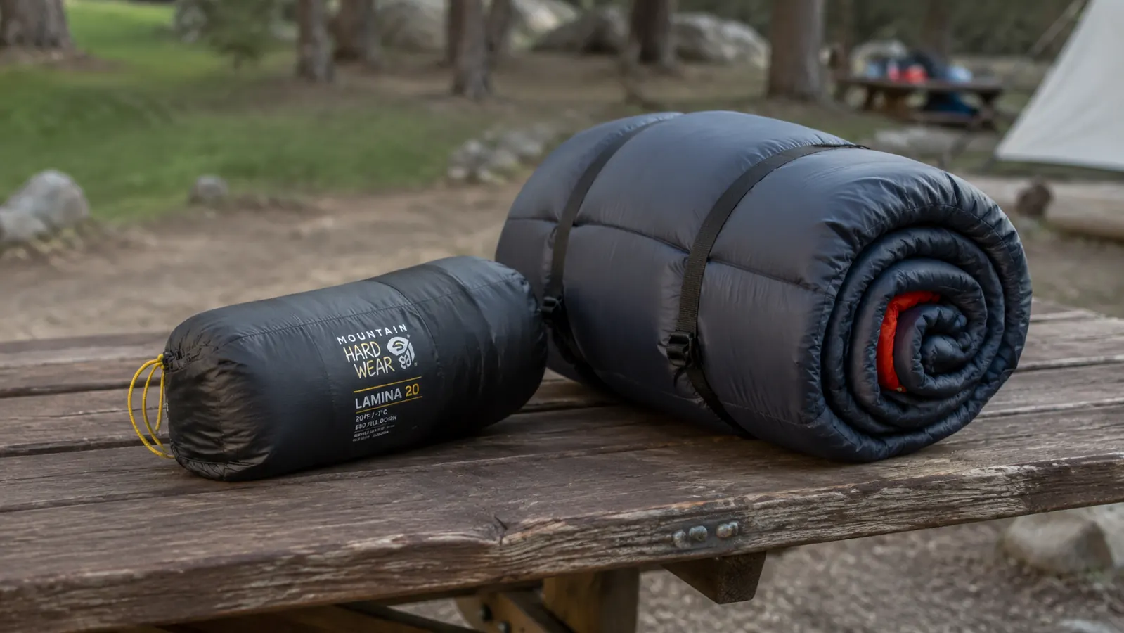 Mummy sleeping bag packed into a compression stuff sack next to a rectangular bag rolled into a large cylinder, demonstrating pack size difference