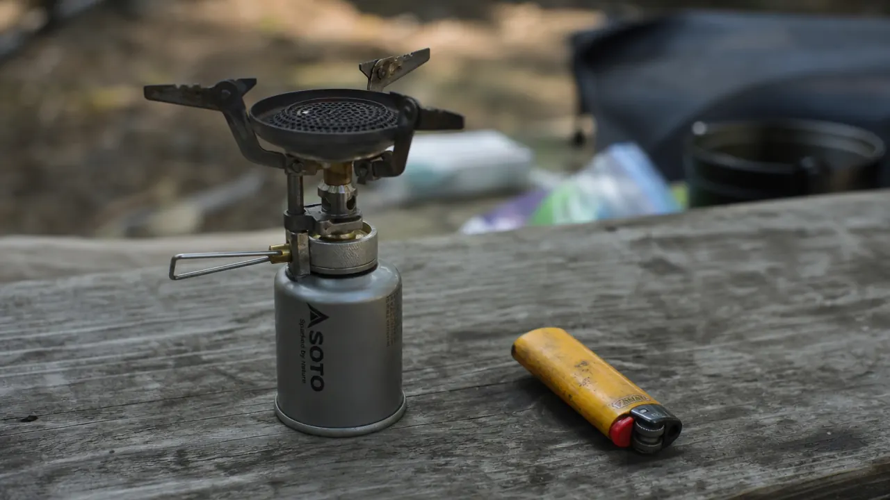 BIC lighter sitting next to an AOTU backpacking stove as a backup ignition method