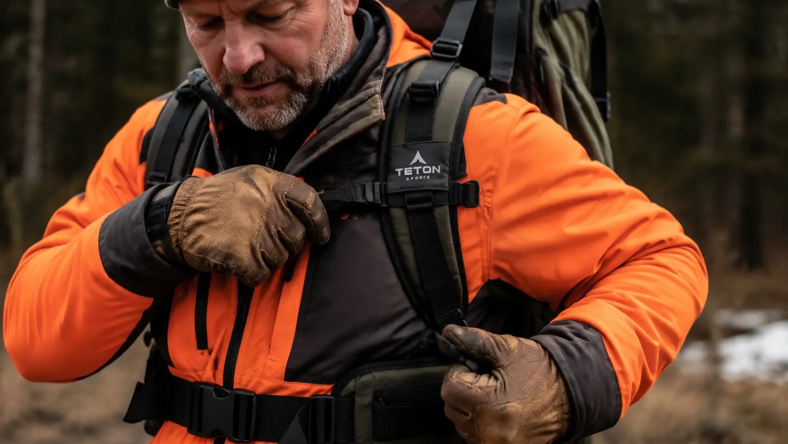 Close-up of a hunter's hands adjusting the hip belt and load lifters on an internal frame backpack