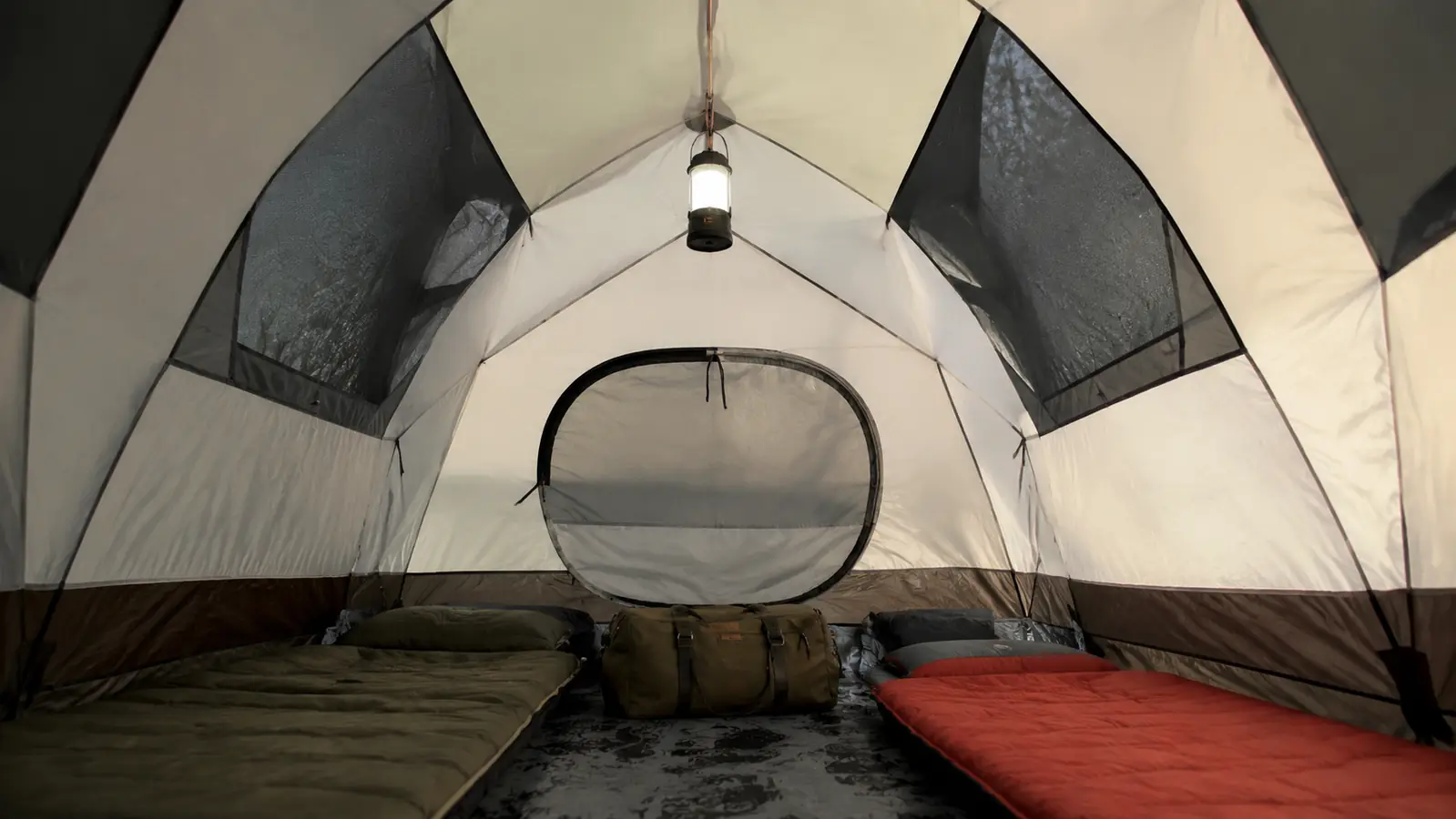 Interior of dome tent showing two sleeping pads and gear bags laid out with headroom visible