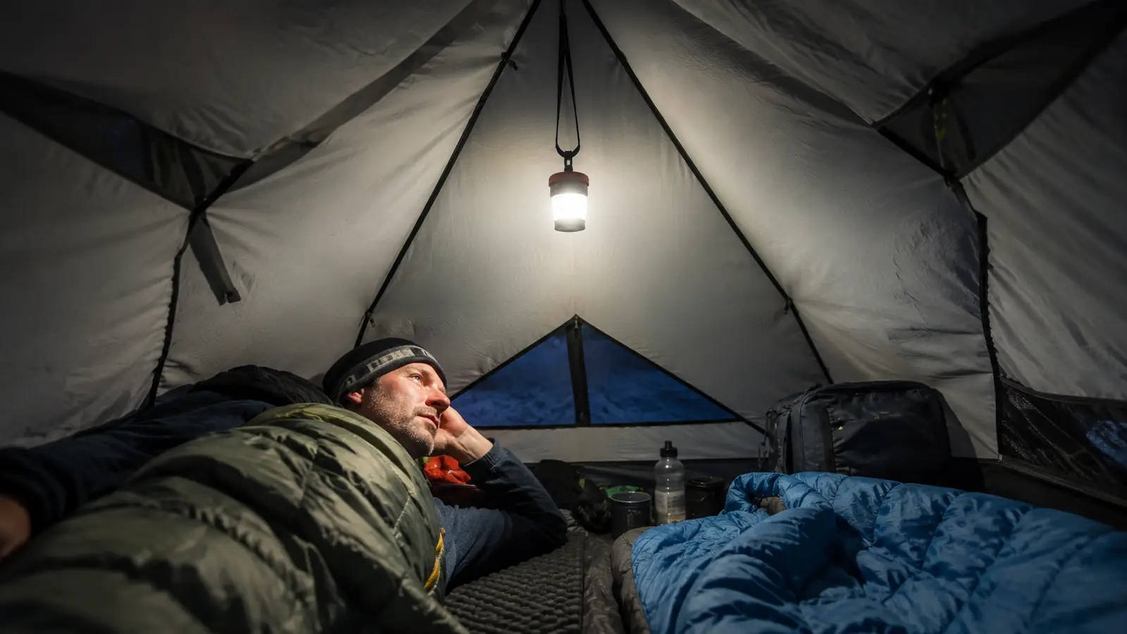 Headlamp mounted on a branch inside a tent to create ambient camp light